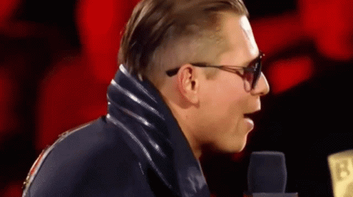 Man in Sunglasses and Blue Jacket at Microphone 13