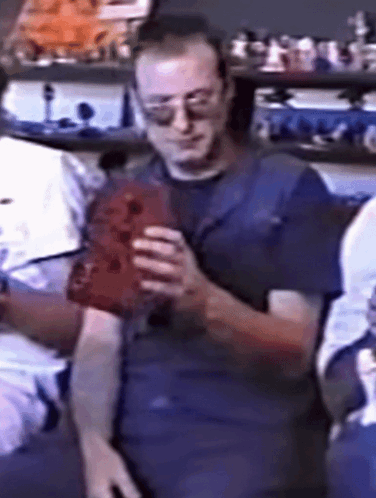 Man in Sunglasses and Blue Shirt Holding Red Object