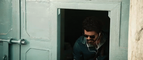 Man in Sunglasses and Earbuds at Doorway