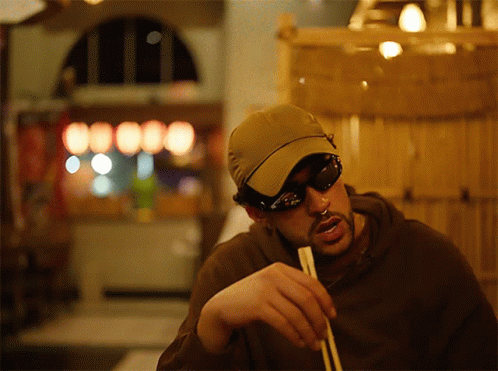 Man in Sunglasses and Hat Holding Chopsticks