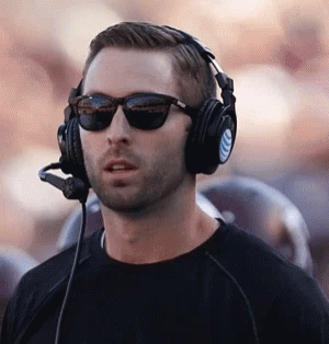 Man in Sunglasses and Headphones With Microphone Standing in Front of Crowd