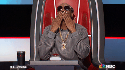 Man In Sunglasses And Necklace Sitting With NBC GIF