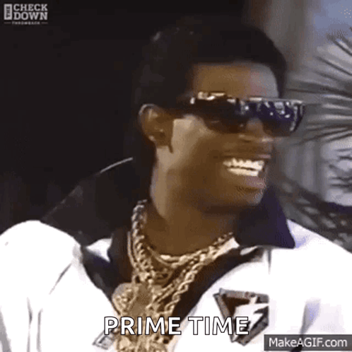 Man in Sunglasses and Necklace Smiling Says Prime Time