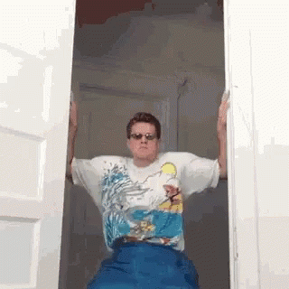 Man In Sunglasses And Simpson Shirt Standing In Open Doorway GIF