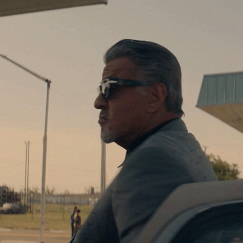 Man in Sunglasses and Suit Sitting in Front of Building