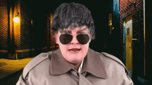 Man in Sunglasses and Trench Coat at Brick Wall