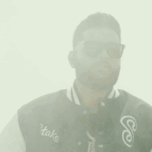 Man in Sunglasses and Varsity Jacket Touching Forehead