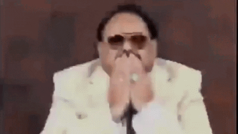 Man in Sunglasses and White Suit Covering Mouth