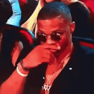 Man In Sunglasses Covering Mouth In Crowd GIF