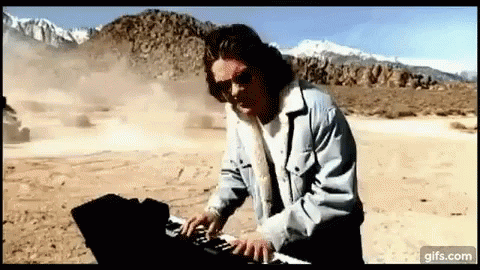 Man in Sunglasses Playing Keyboard in Desert