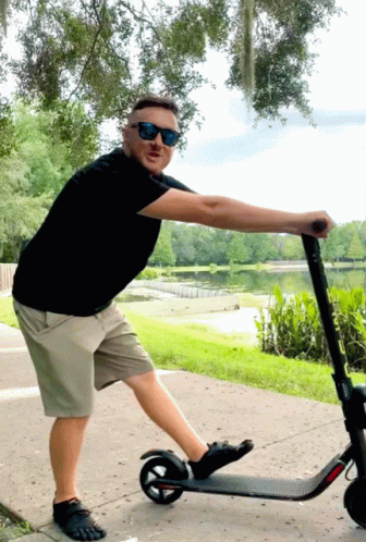 Man in Sunglasses Pushing Scooter