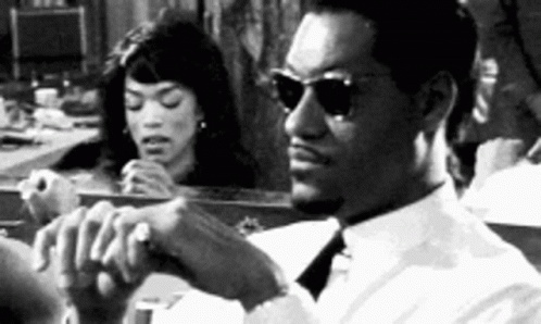 Man in Sunglasses Sitting in Front of Mirror With Woman Looking