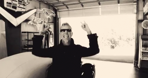 Man In Sunglasses Sitting In Garage Arms Outstretched GIF