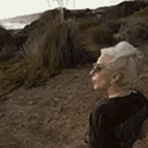 Man In Sunglasses Standing On Dirt Path Looking At Ocean GIF