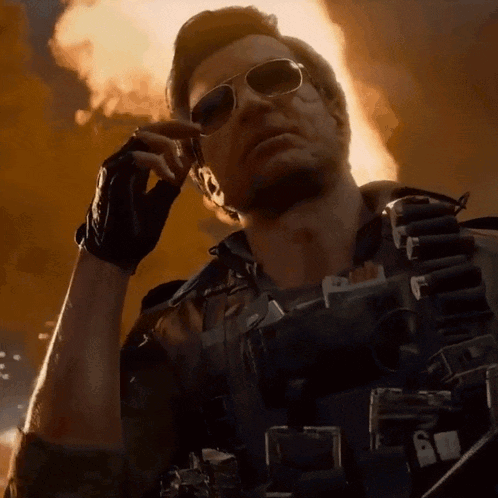 Man In Sunglasses Talking On Cell Phone In Front Of Fire GIF