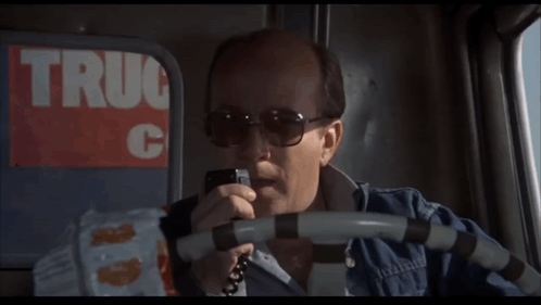 Man in Sunglasses Talking on Phone in Front of Truck C Sign