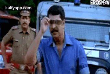 Man in Sunglasses With Police Car and Officer