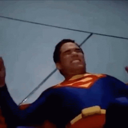 Man in Superman Costume Laying on Ground With Hands Up