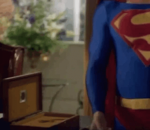Man in Superman Costume Standing Next to Cigar Box