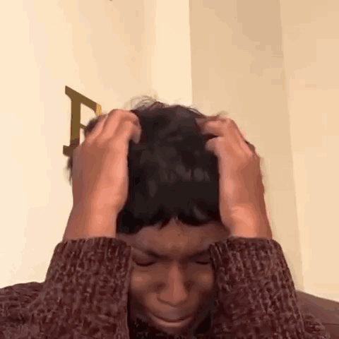 Man in Sweater Holding Head in Pain