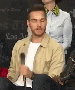 Man in Tan Jacket Sitting at Microphone