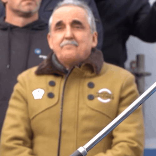 Man in Tan Jacket With NC Sticker