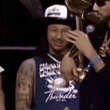 Man in Thunder Jersey Holding Trophy, Onlooker