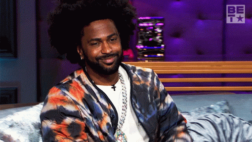 Man in Tie Dye Jacket Smiling on Bed