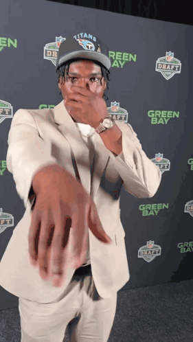 Man In Titans Hat Covering Mouth GIF