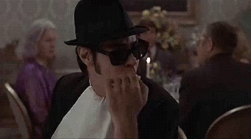 Man in Top Hat and Sunglasses Sitting at Table With Candle