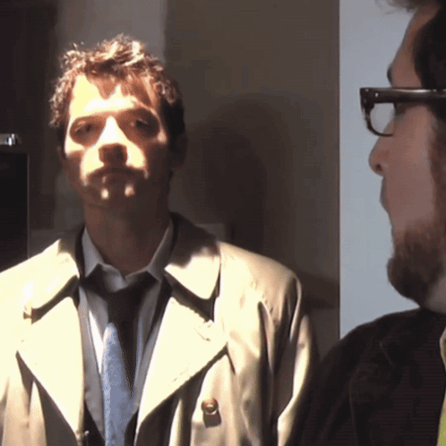 Man in Trench Coat and Tie Next to Man in Glasses