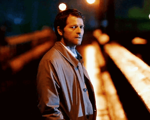 Man in Trench Coat and Tie on Train Track at Night