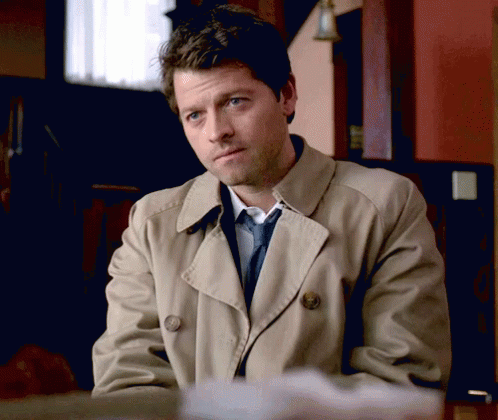 Man in Trench Coat and Tie Sitting at Desk