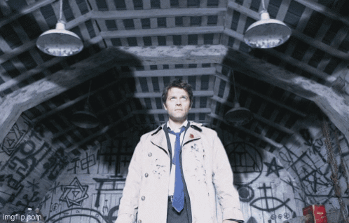 Man in Trench Coat and Tie Standing in Dark Room