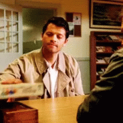 Man in Trench Coat Sitting at Table With Another Man