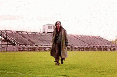 Man in Trench Coat Walking on Soccer Field