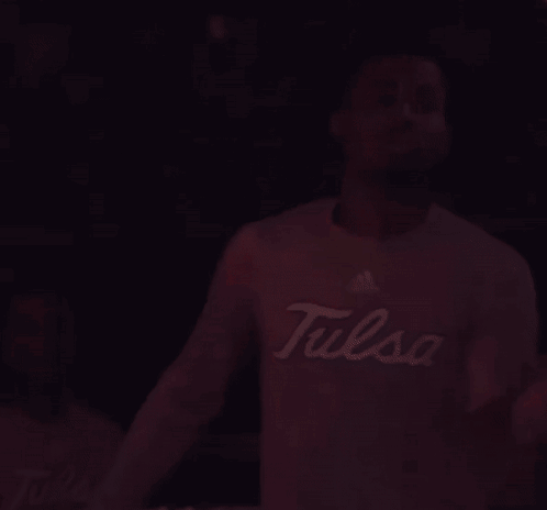 Man in Tulsa Shirt Standing in Dark Room