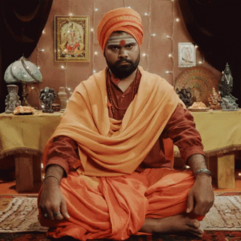 Man In Turban And Orange Robe At Table GIF