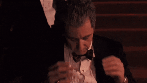 Man in Tuxedo Adjusting Bow Tie in Dark Room