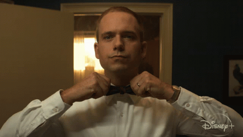 Man in Tuxedo Adjusting Bow Tie in Front of Disney Plus Sign