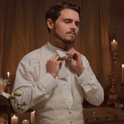 Man in Tuxedo Adjusting Bow Tie with Candles