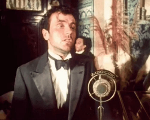 Man In Tuxedo And Bow Tie At Microphone GIF