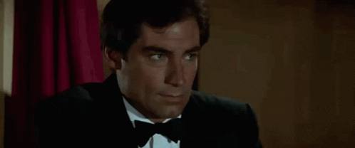 Man In Tuxedo And Bow Tie Sitting In Chair GIF