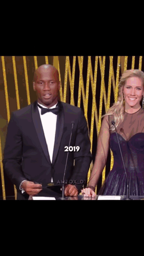 Man in Tuxedo and Woman in Purple Dress at Podium 2019