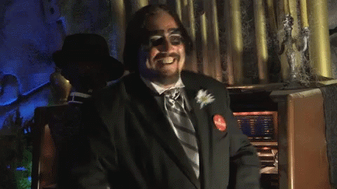 Man in Tuxedo Clapping in Front of Statue