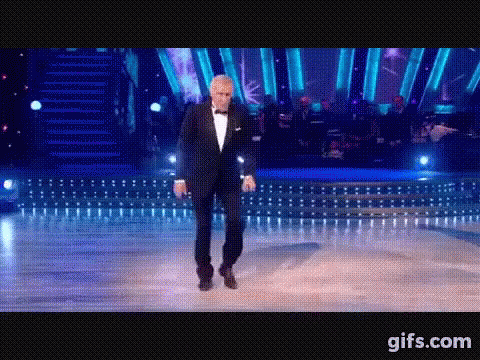 Man In Tuxedo Dancing In Front Of Orchestra GIF