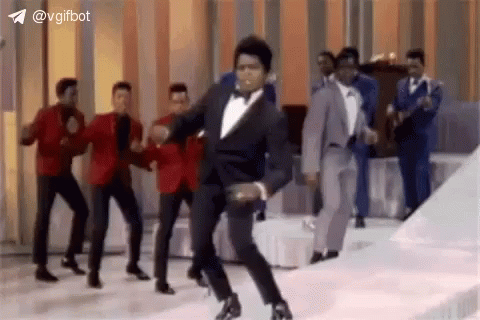 Man in Tuxedo Dancing With Suited Men on Stage