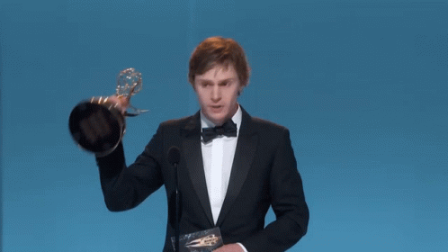 Man in Tuxedo Holding Emmy Trophy