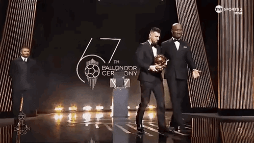 Man In Tuxedo Holding Soccer Ball On Stage GIF