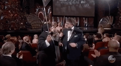 Man In Tuxedo Holding Trophy At Awards Show GIF